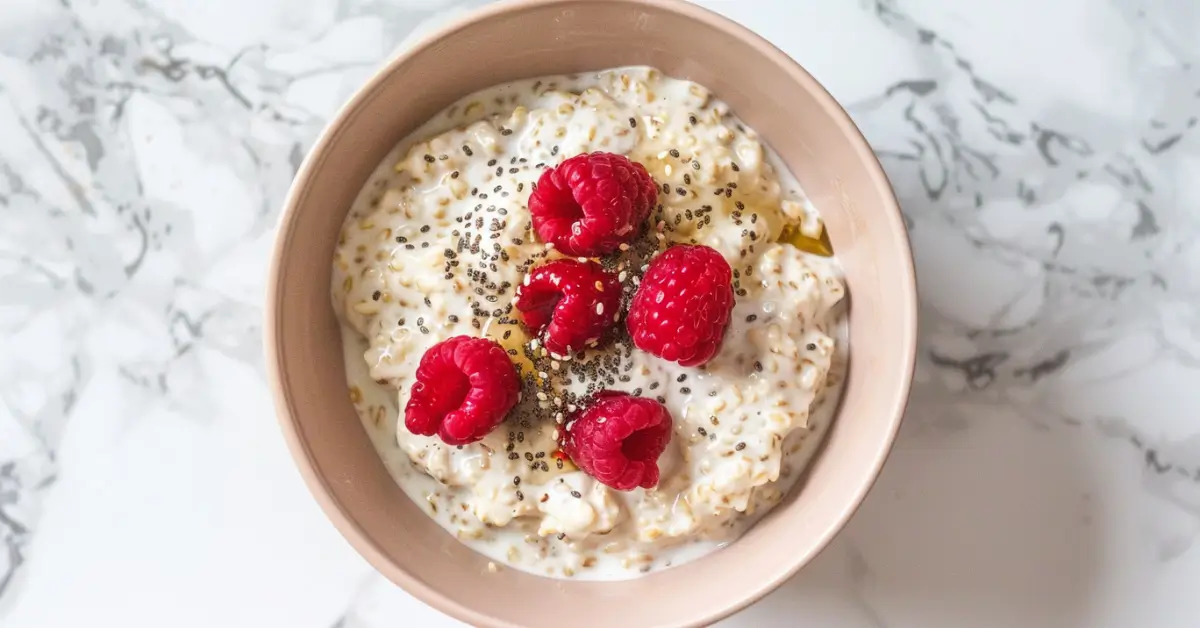 High-Protein Overnight Oats - High-protein overnight oats in a pink bowl with chia seeds, honey, and raspberries